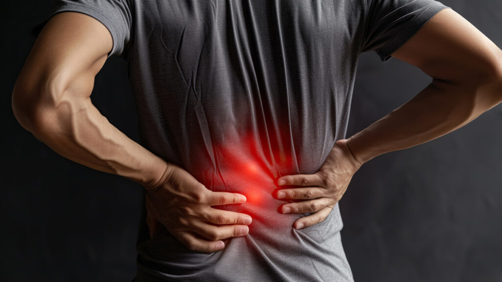 Man in a gray shirt holding his lower back with both hands, with a red glow indicating pain. Blue-Emu helps relieve back discomfort fast.